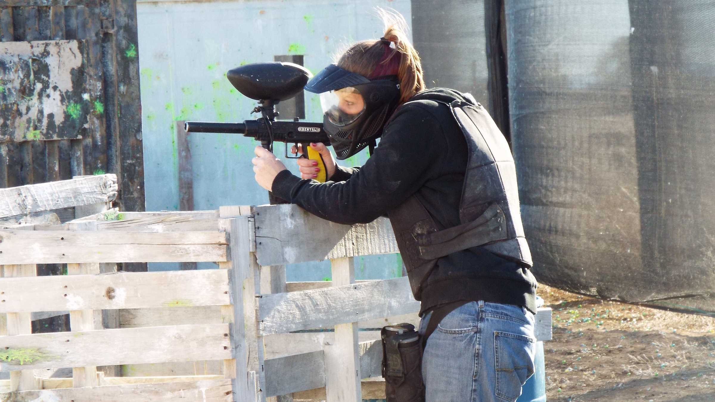 Woman aiming and shooting paintball gun